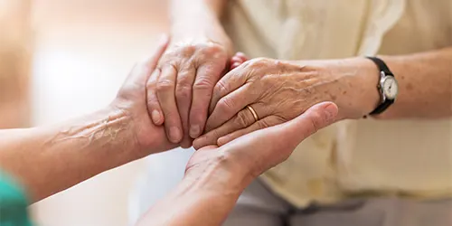 Caregiver holding relative’s hands.