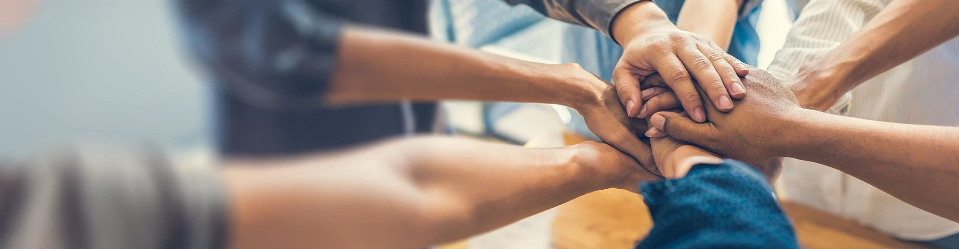 Teammates placing hands atop each other in a circle