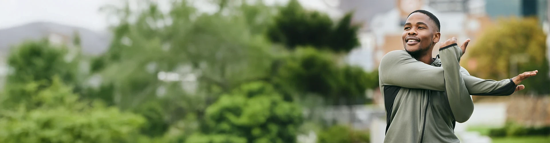 A man stretches out his arms while outside. 