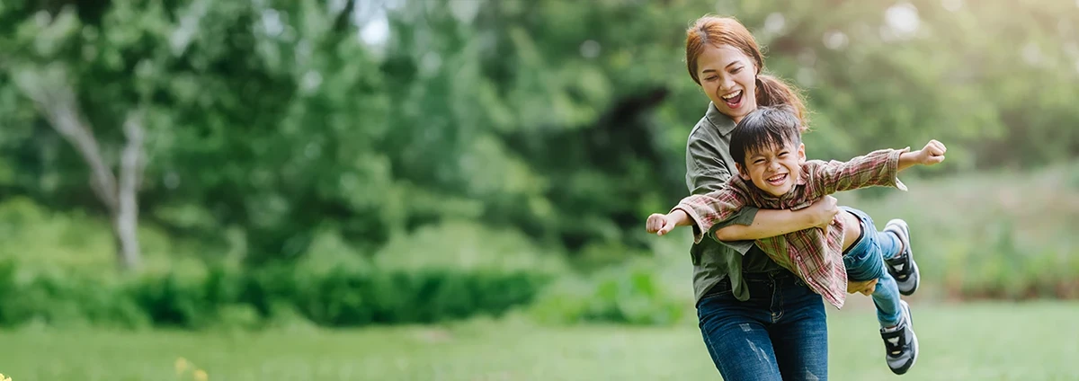 Smiling woman and child play outdoors