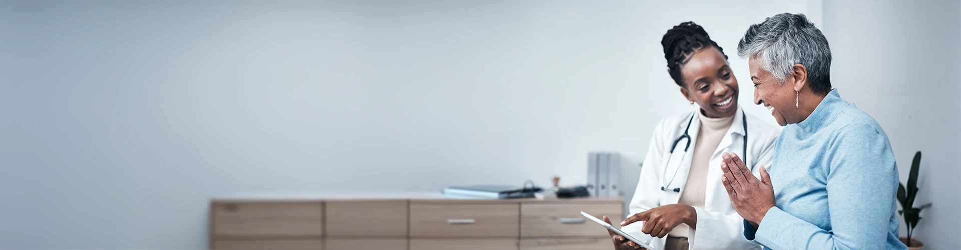 A doctor and patient look at a tablet together in an office setting. 