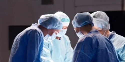 Three caregivers standing around operating table.